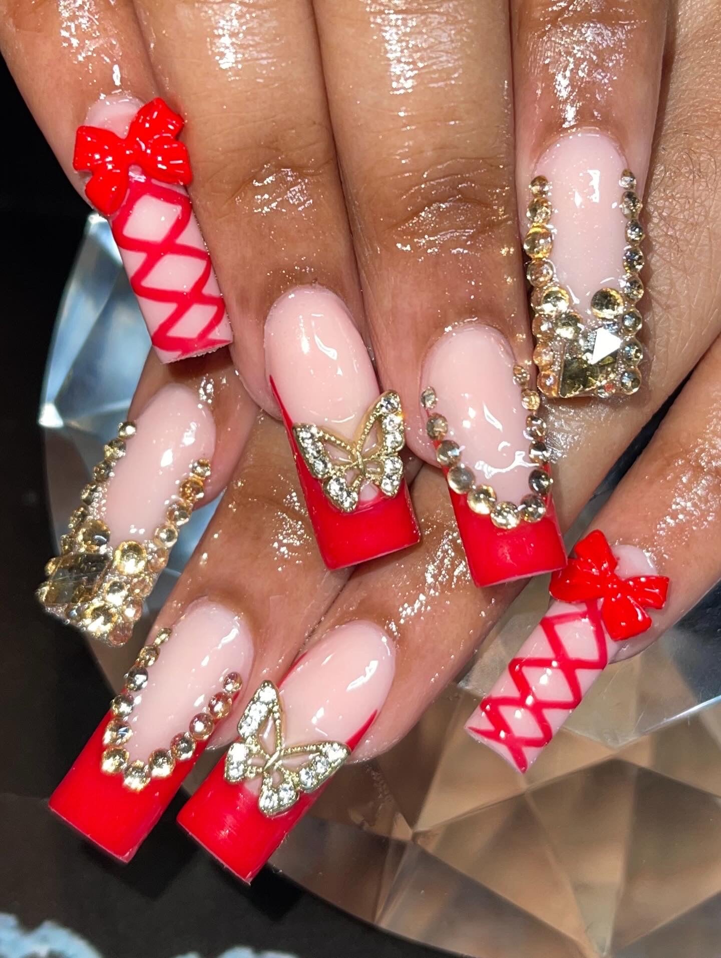 Nails with red and gold decorations on a reflective surface