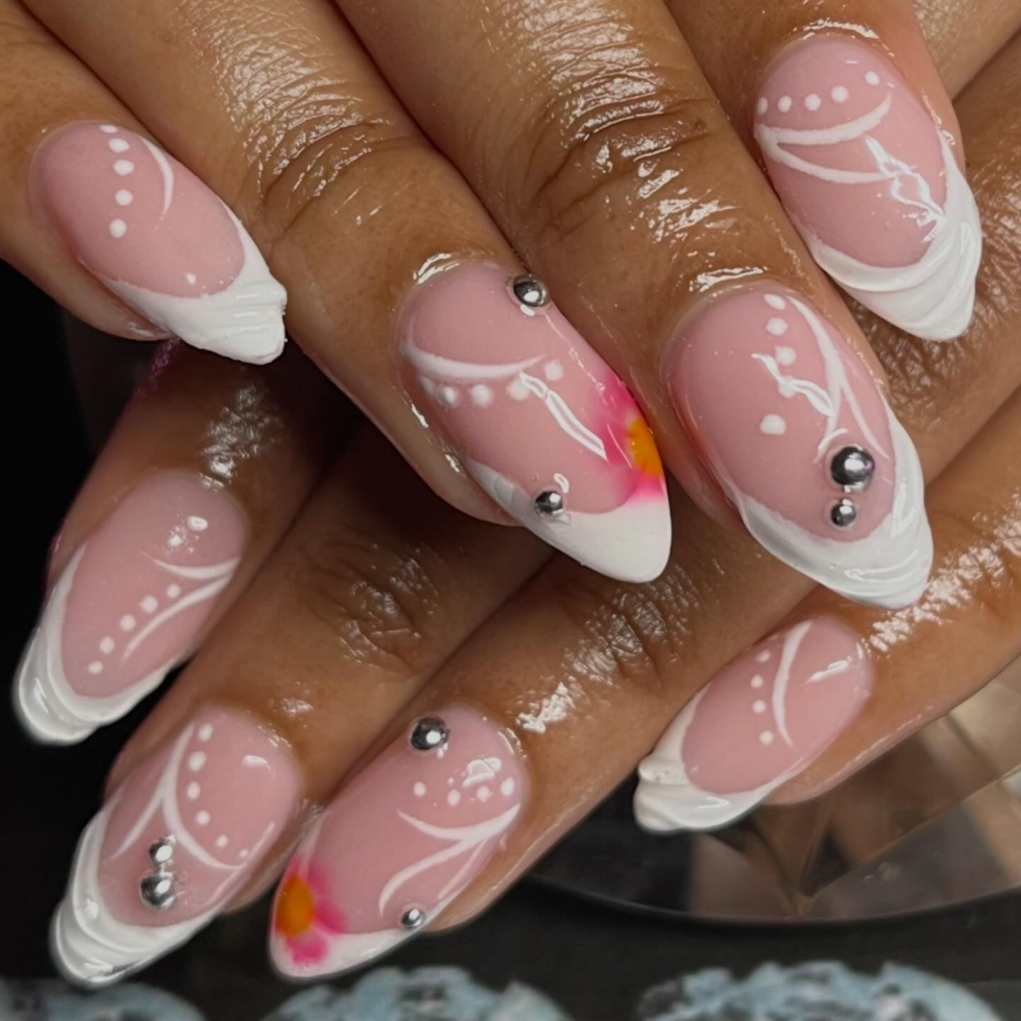 Close-up of hands with pink and white nail art featuring decorative elements.