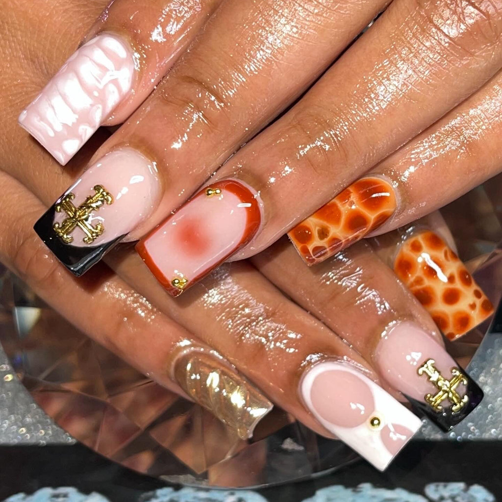 Close-up of a hand with variously designed nails featuring gold accents.