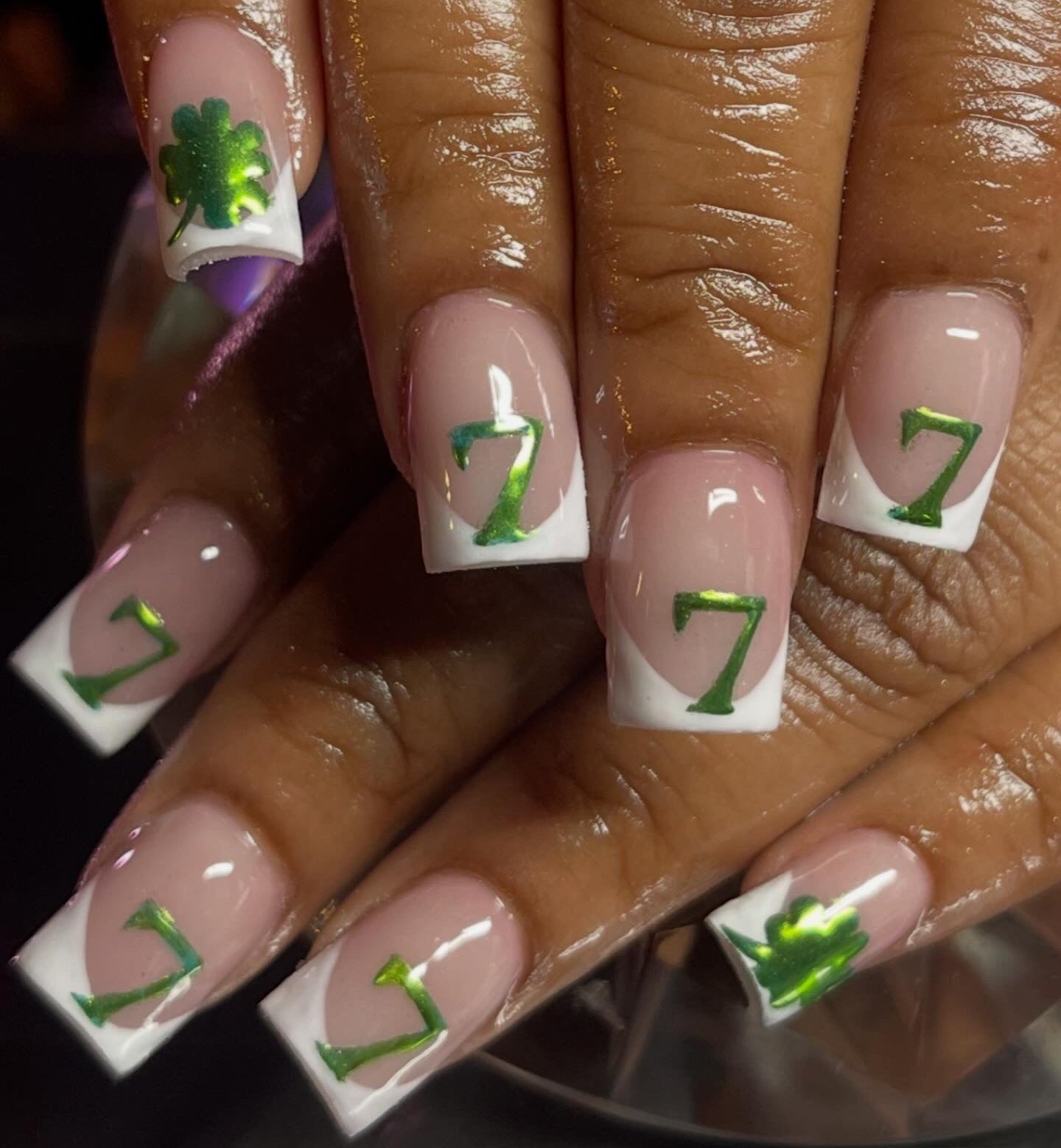 Nails with green number '7' and clover design on a white background